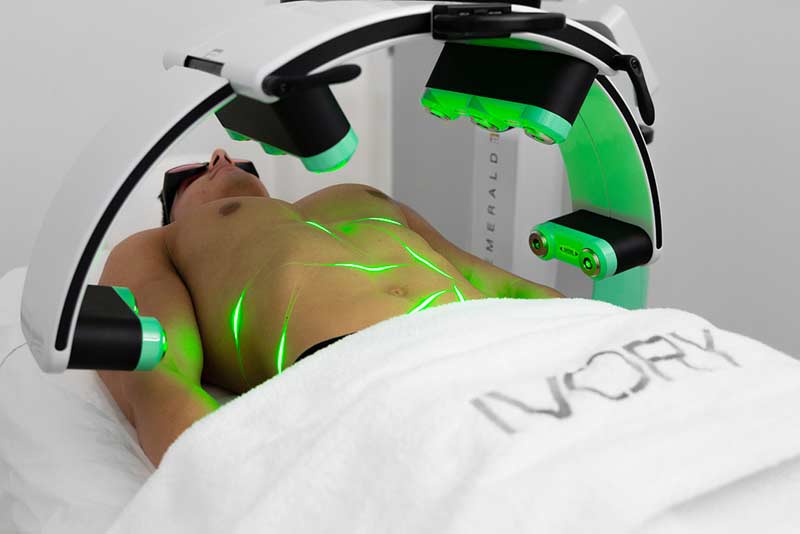 Male body sculpting patient on a table with green lasers on his midsection